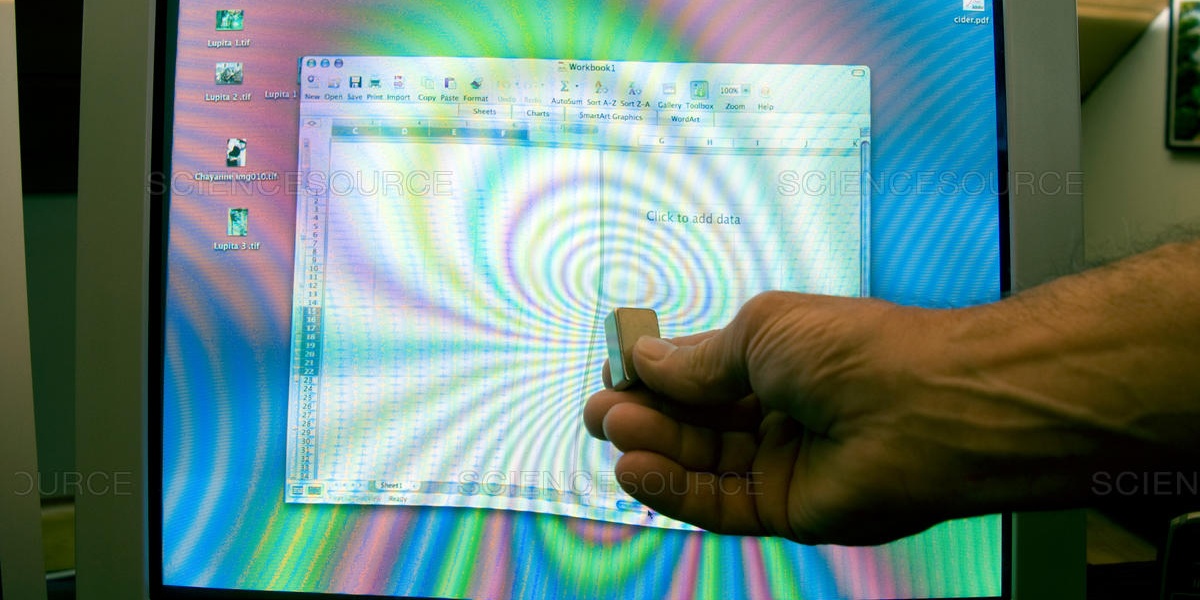 Hand pressing against a damaged monitor screen showing distorted colours