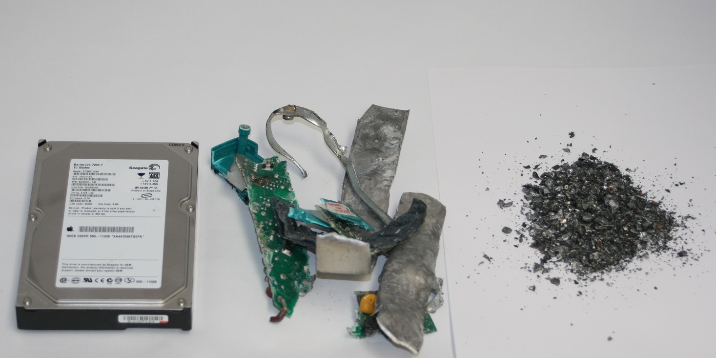 Hard drive shown beside its shredded remains and fine metal granulate