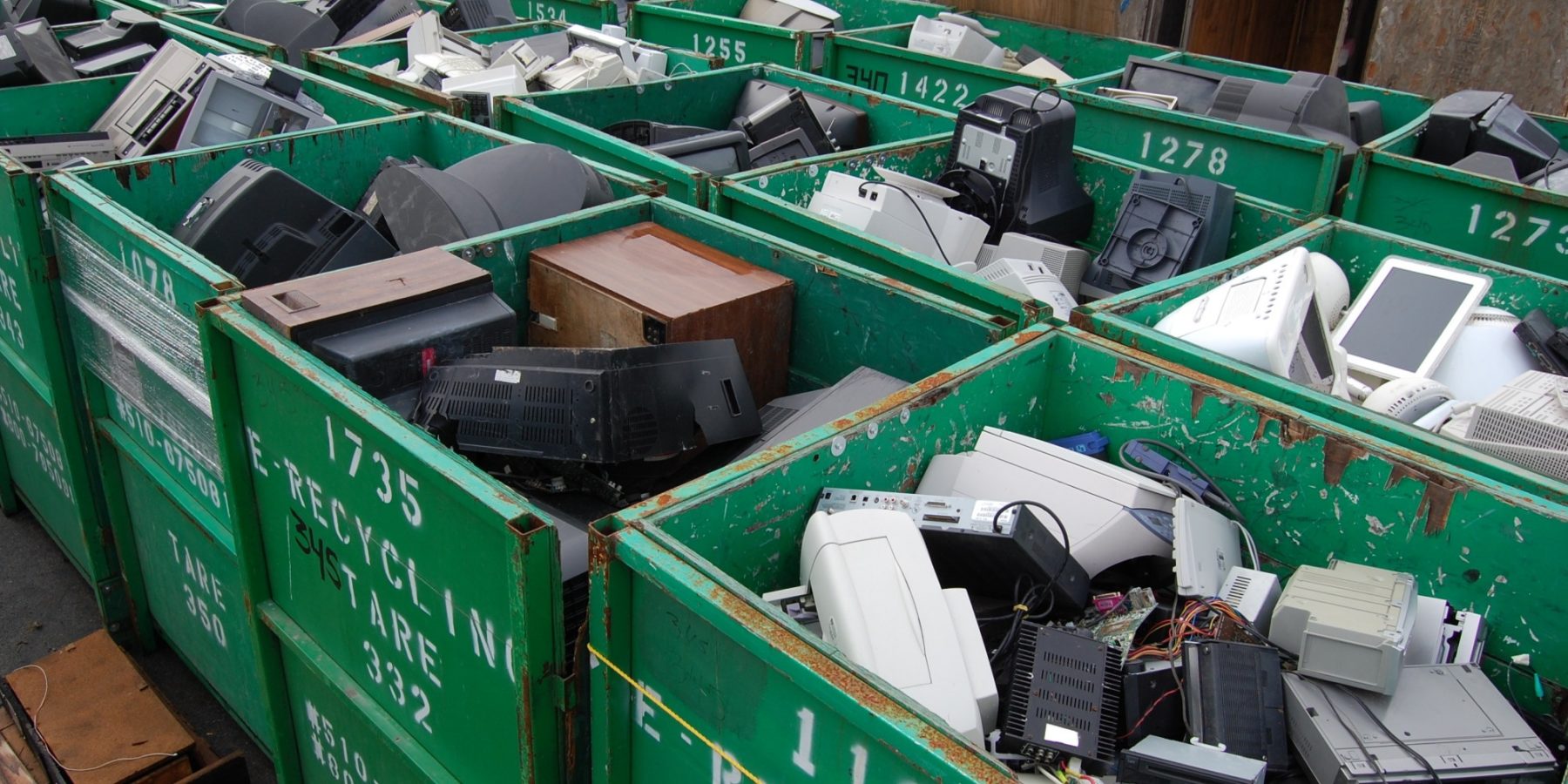 Green skips filled with discarded monitors, printers and computer casings