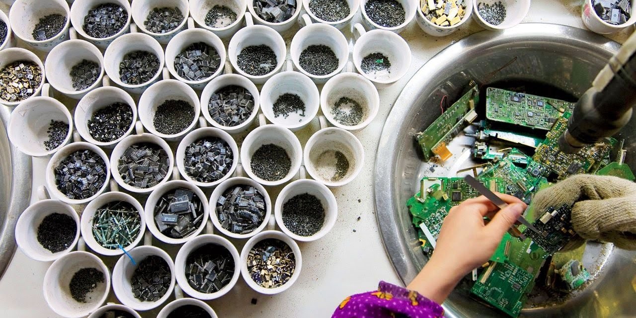 Gloved hand sorting circuit boards beside tubs of separated components