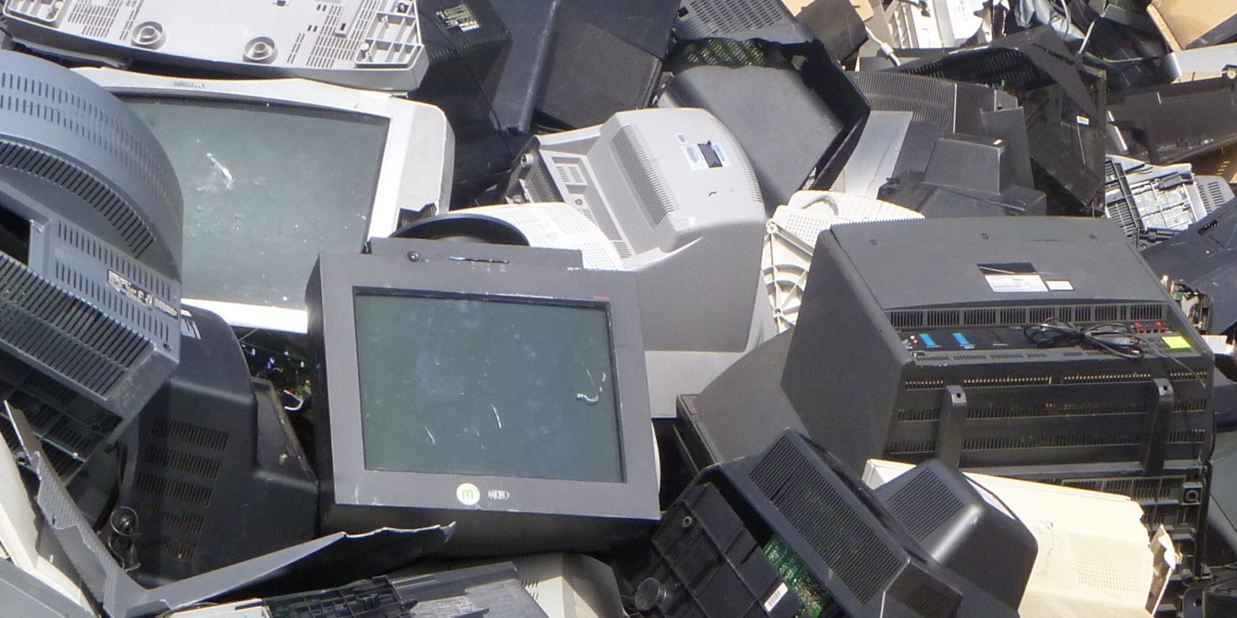Heap of discarded office electronics including monitors and printers