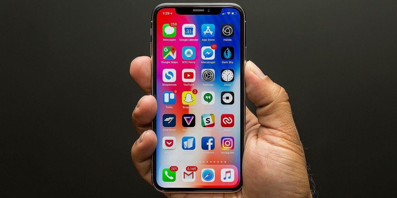 Hand holding a smartphone displaying a grid of app icons
